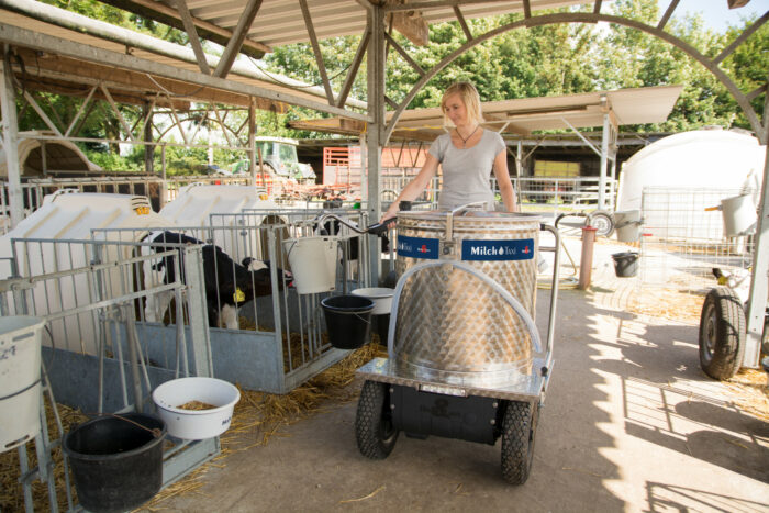 Dieses Bild zeigt eine Landwirtin mit MilchTaxi im KälberGarten. Sie dosiert Milch in einen Saugeimer.